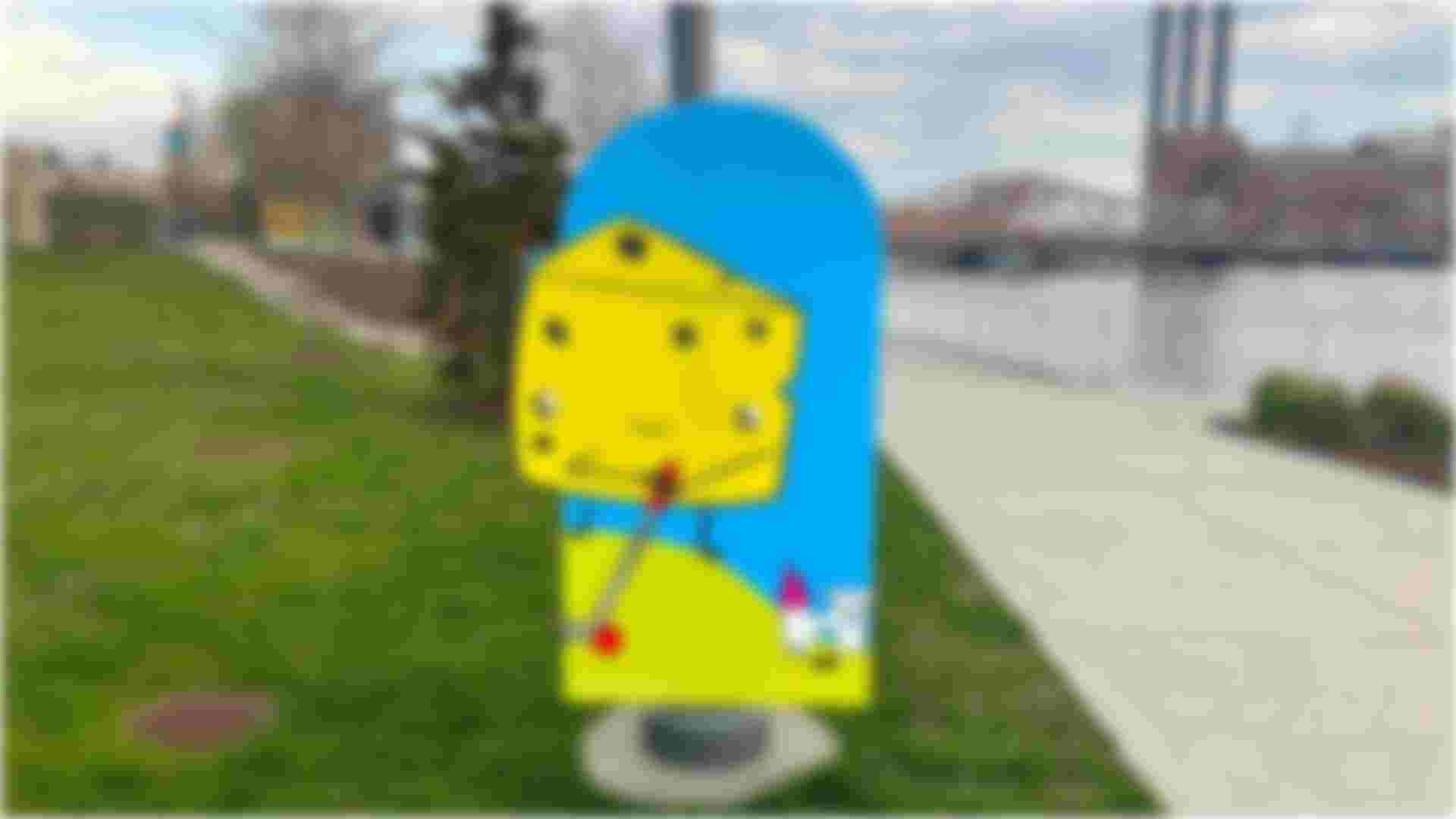 A large 5 ft tall character cutout of a triangle of cheese playing mini golf attached to a light pole in 195 District Park